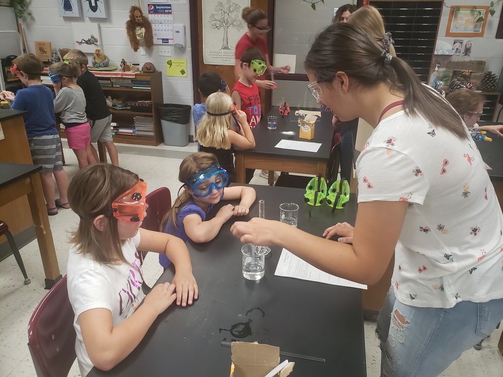 First grade students work with high school student on an experiment